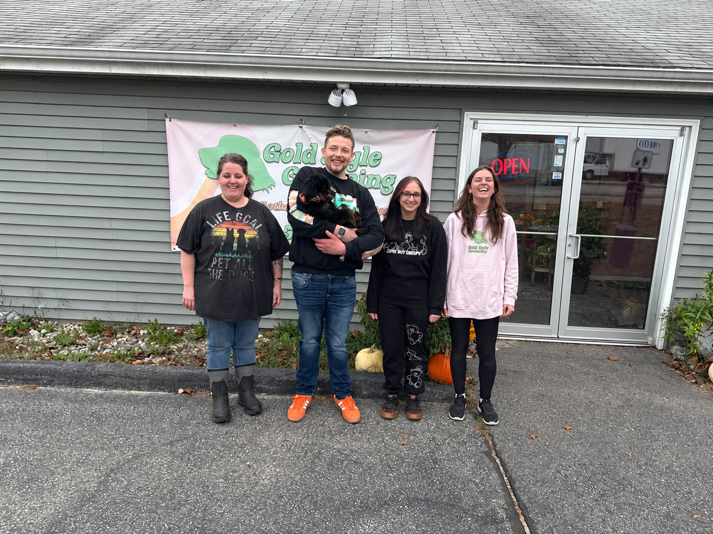 Four Gold Style team members standing outside the salon, with one holding a small black dog.